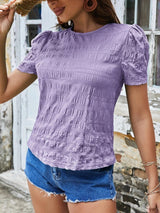 a woman wearing a purple top and denim shorts