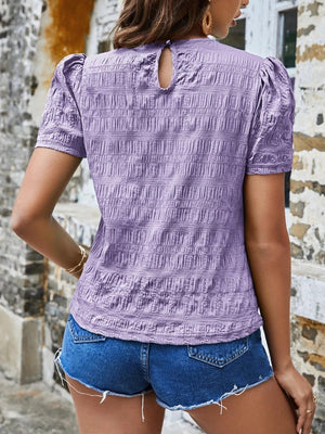 a woman wearing a purple top and denim shorts