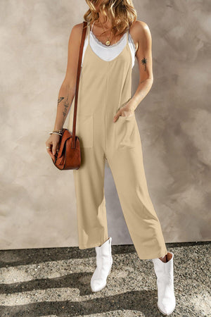 a woman in a tan jumpsuit holding a brown purse