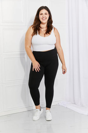 a woman in a white tank top and black leggings