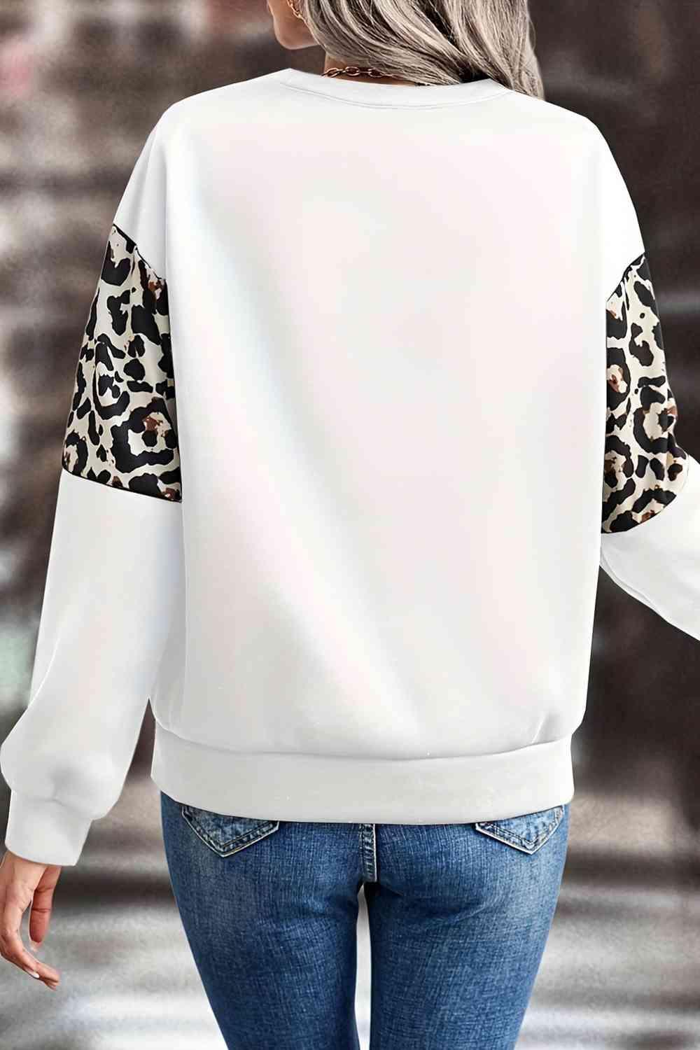 a woman wearing a white sweatshirt with leopard print sleeves