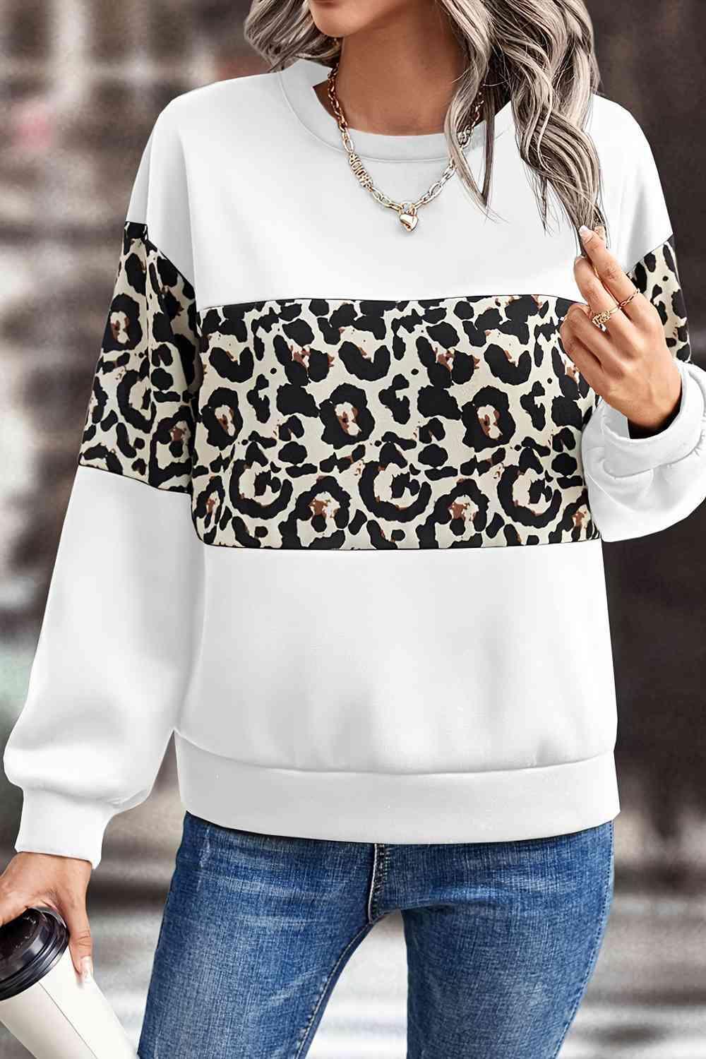 a woman wearing a white sweater with a leopard print on it