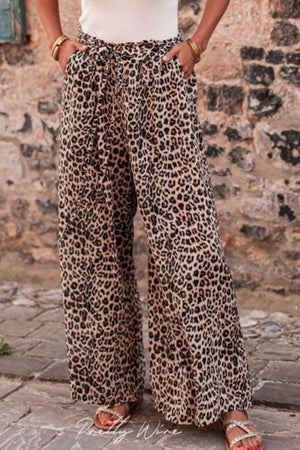 a woman wearing a white tank top and leopard print pants