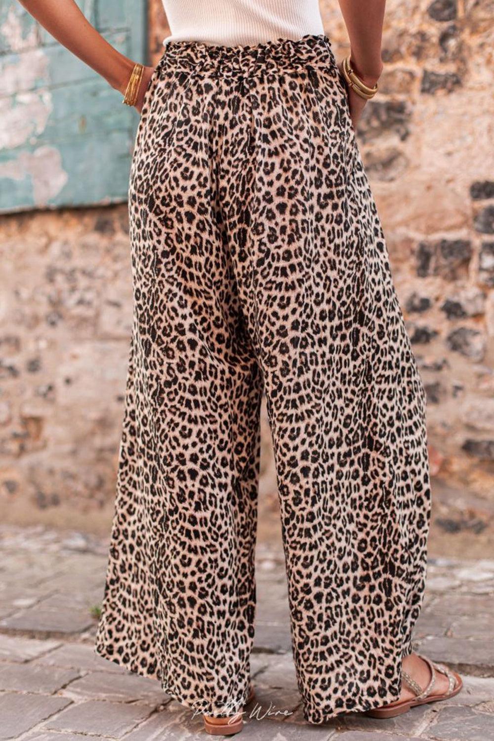 a woman wearing a white tank top and leopard print pants