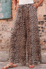 a woman wearing a white tank top and leopard print pants