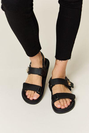 a close up of a person wearing black sandals