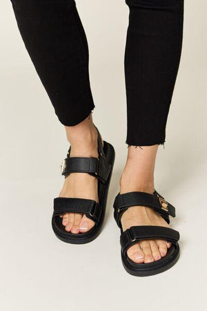 a close up of a person wearing black sandals