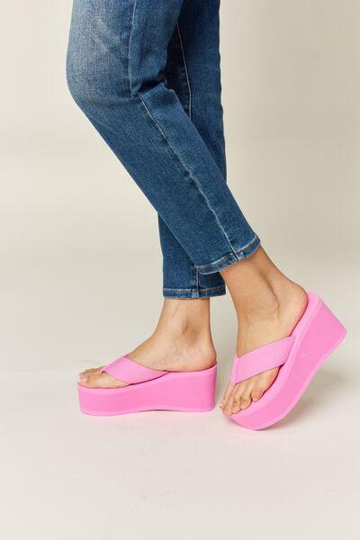 a woman's feet in pink sandals and jeans