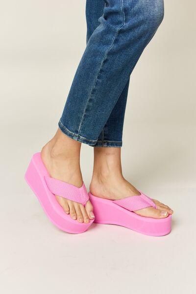 a woman's feet wearing pink sandals and jeans
