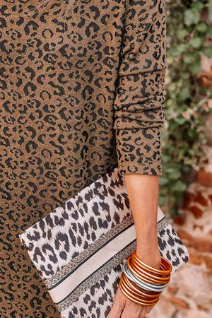 a woman holding a leopard print clutch bag