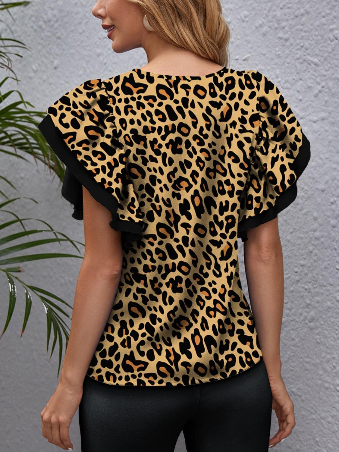 a woman wearing a leopard print top and black pants