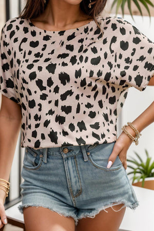 a woman wearing a leopard print top and denim shorts