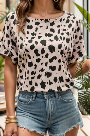 a woman wearing a leopard print top and denim shorts