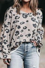 a woman wearing a leopard print sweater and ripped jeans