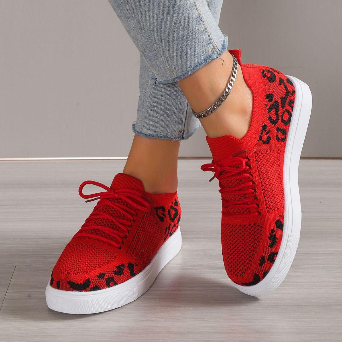 a woman wearing red sneakers with leopard print