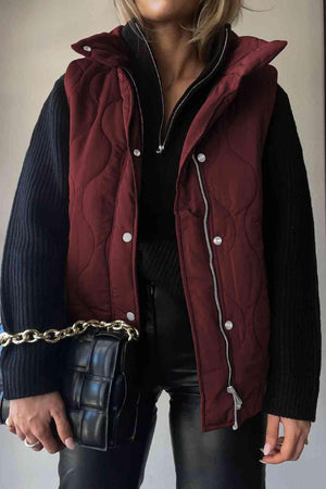 a woman wearing a red quilted vest and black leather pants
