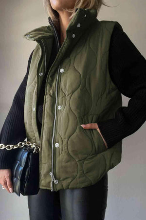 a woman wearing a green quilted vest and black pants