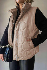 a woman wearing a tan quilted vest and black pants