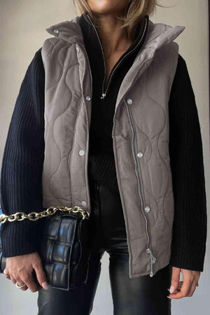 a woman wearing a gray quilted vest and black pants