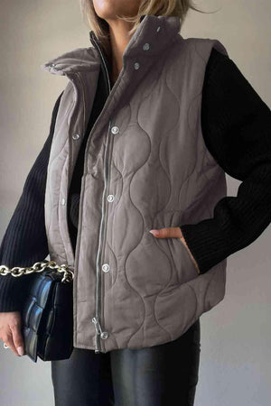 a woman in a gray vest holding a black purse