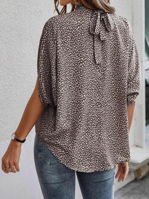 a woman wearing a leopard print blouse and jeans