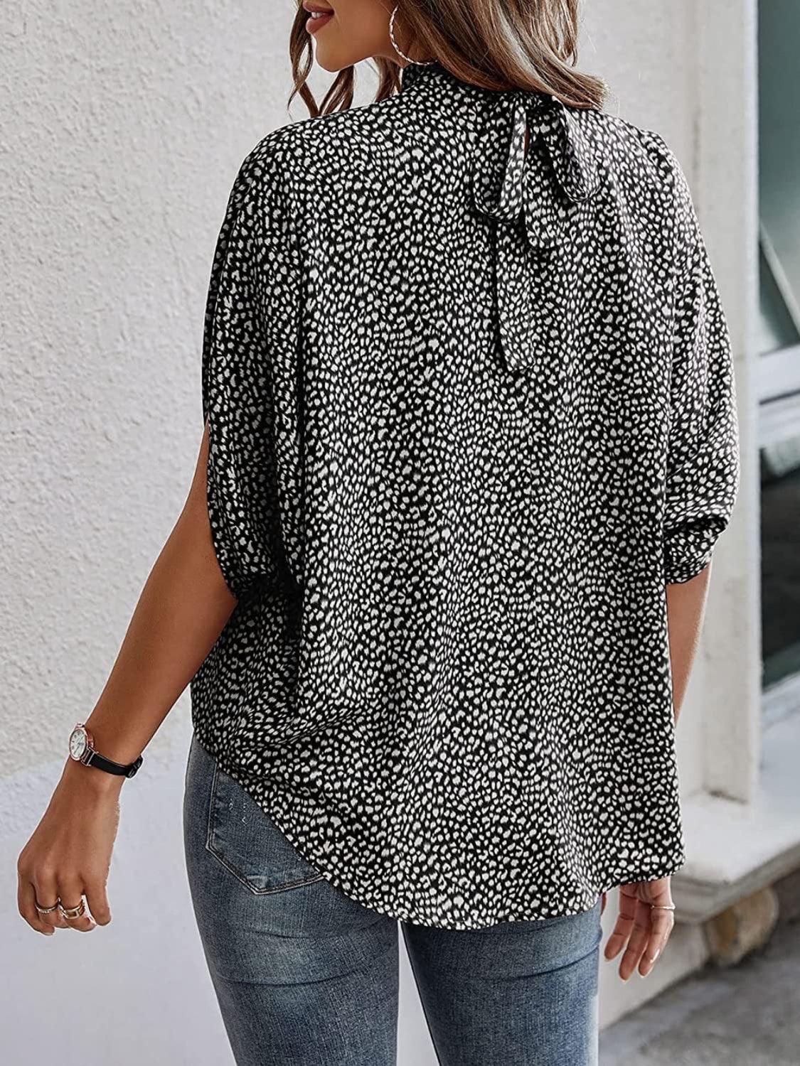 a woman wearing a black and white blouse and jeans