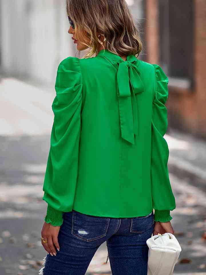 a woman wearing a green blouse and jeans