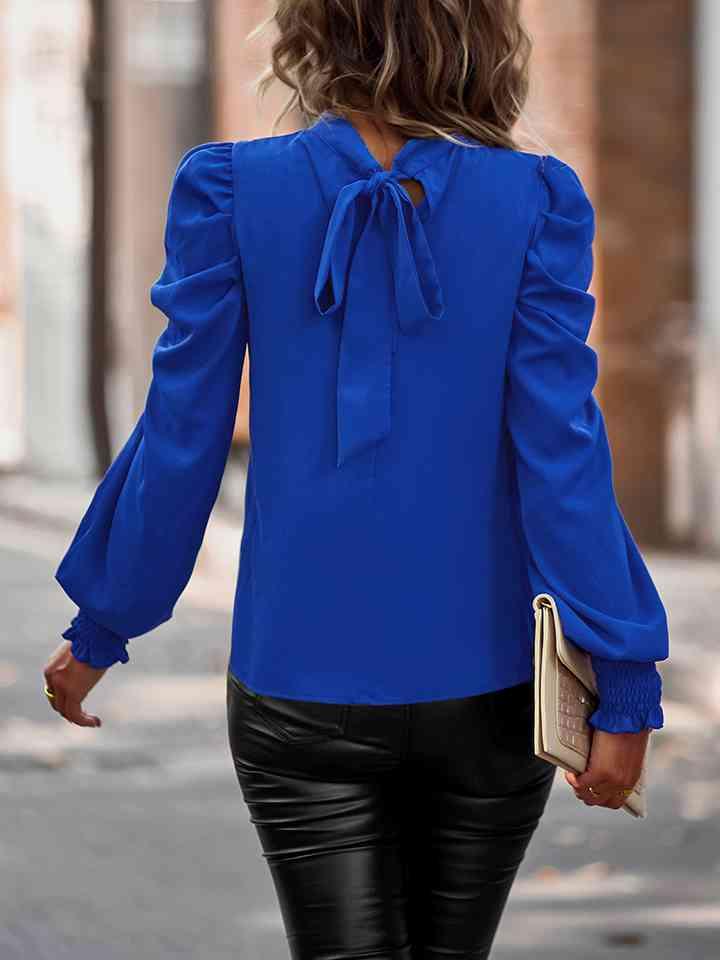 a woman wearing a blue blouse and black pants