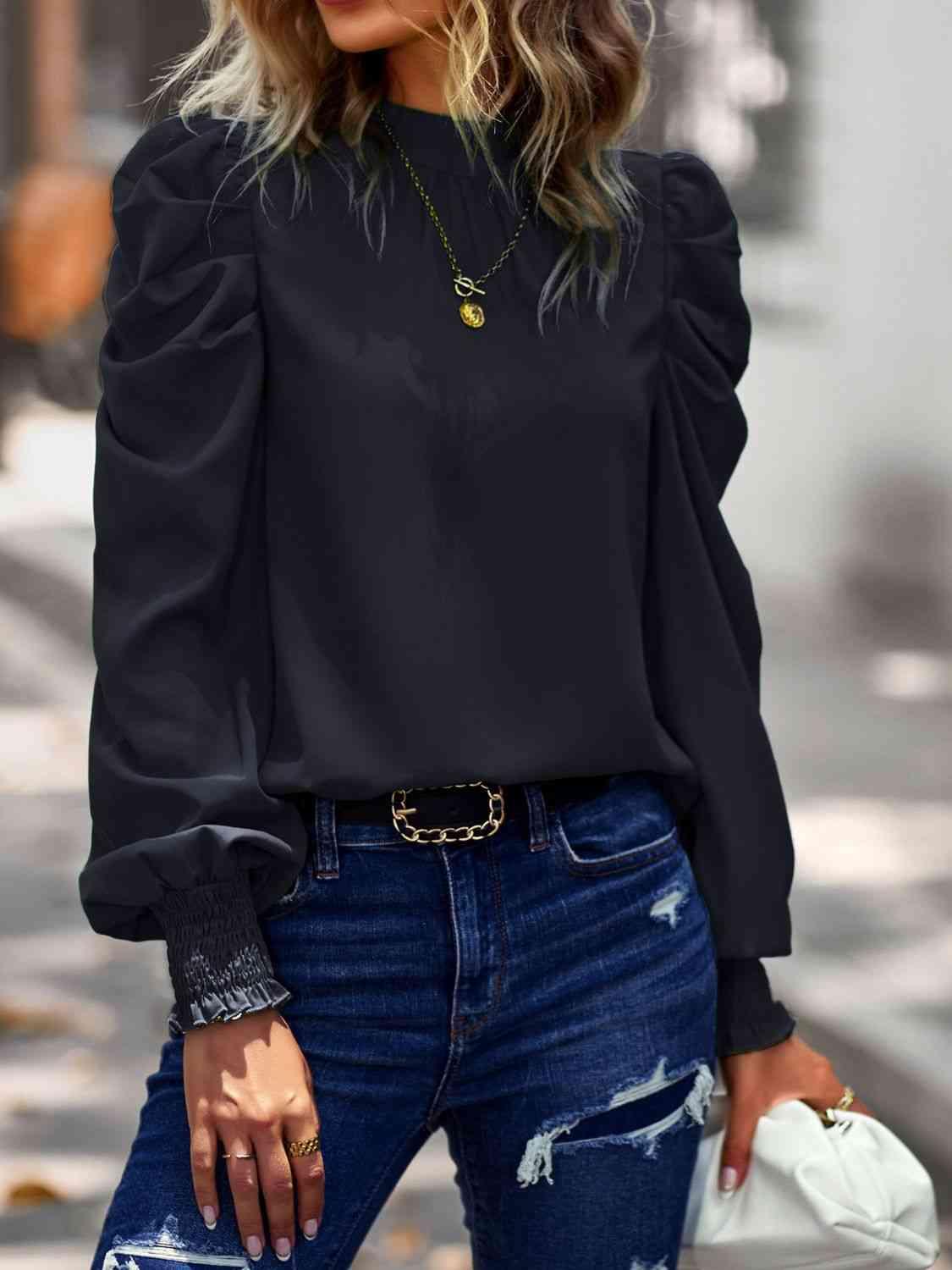 a woman wearing a black blouse and ripped jeans