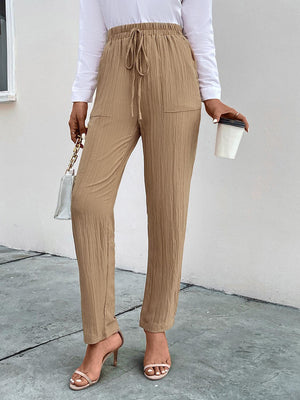 a woman in a white shirt and tan pants holding a cup of coffee