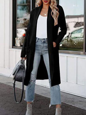 a woman wearing a long black coat and ripped jeans
