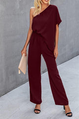 a woman wearing a burgundy jumpsuit with a one shoulder top