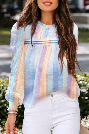 a woman wearing a colorful striped top and white pants