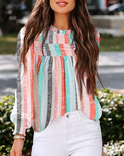 a woman with long brown hair wearing a colorful top