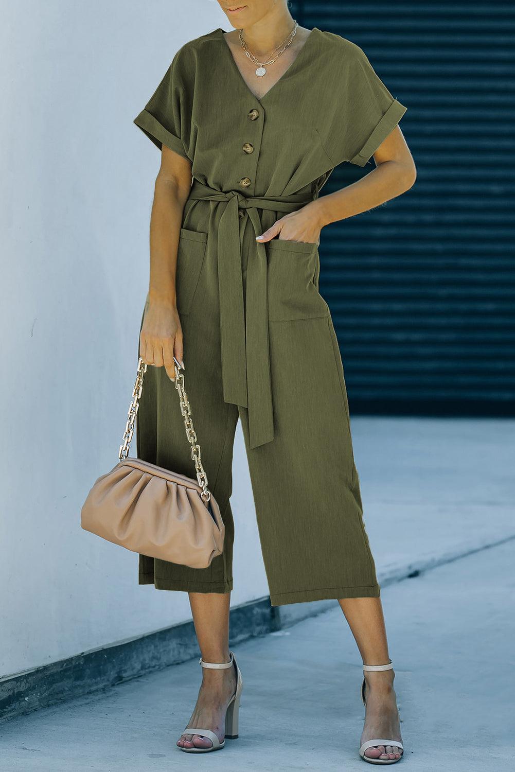 a woman in a green jumpsuit holding a handbag