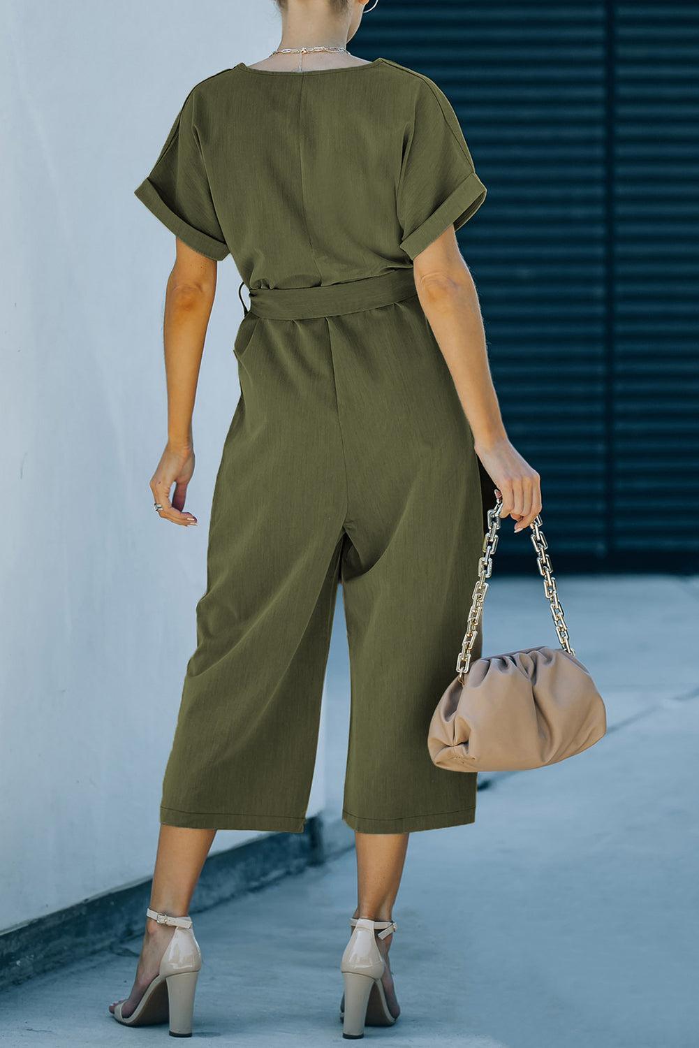 a woman in a green jumpsuit carrying a beige bag