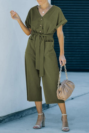 a woman in a green jumpsuit holding a handbag