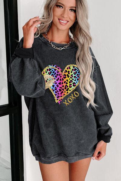 a woman wearing a black sweater with a heart on it
