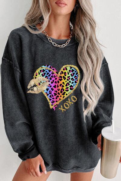 a woman wearing a black sweater with a leopard heart on it