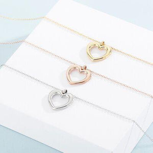 three heart necklaces sitting on top of a white box