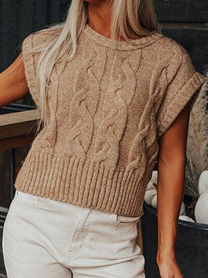 a woman wearing a tan sweater and white pants