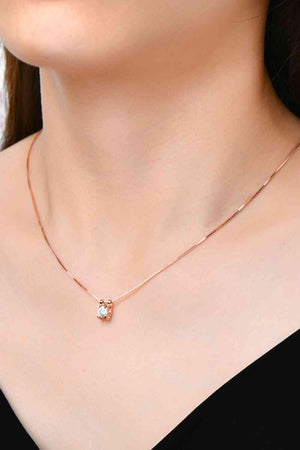 a woman wearing a necklace with a diamond on it