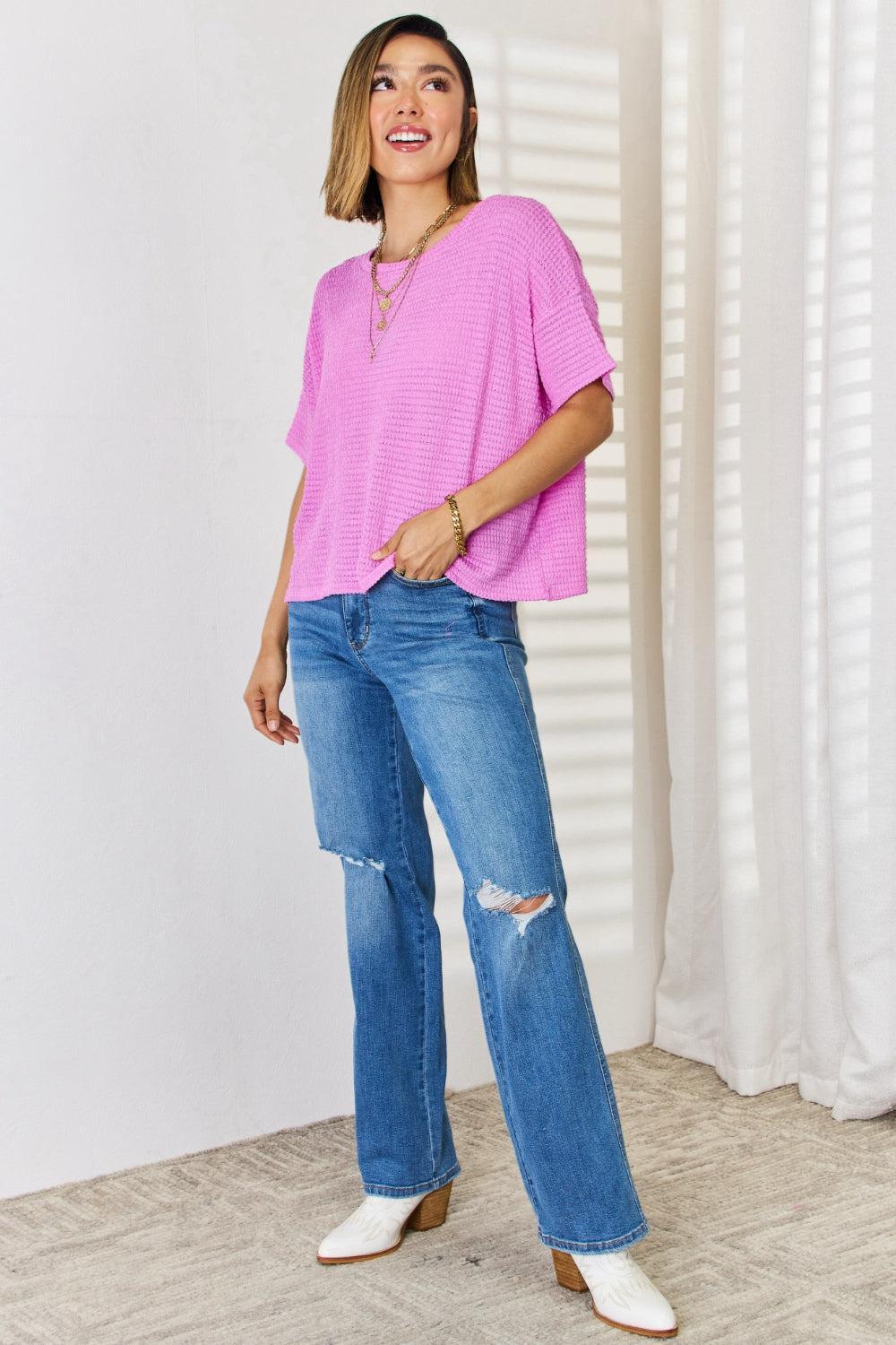 a woman wearing a pink top and jeans