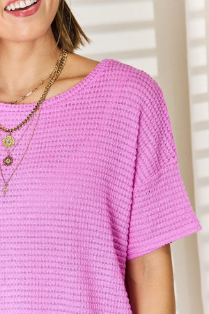 a woman wearing a pink shirt and a necklace