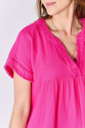 a woman wearing a pink top and a necklace