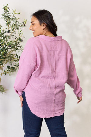 a woman standing next to a plant wearing a pink shirt