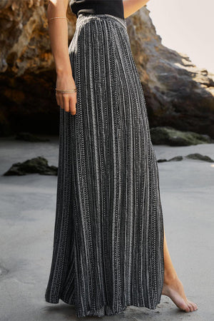 a woman standing on a beach wearing a black and white dress