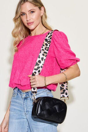 a woman in a pink top holding a black purse