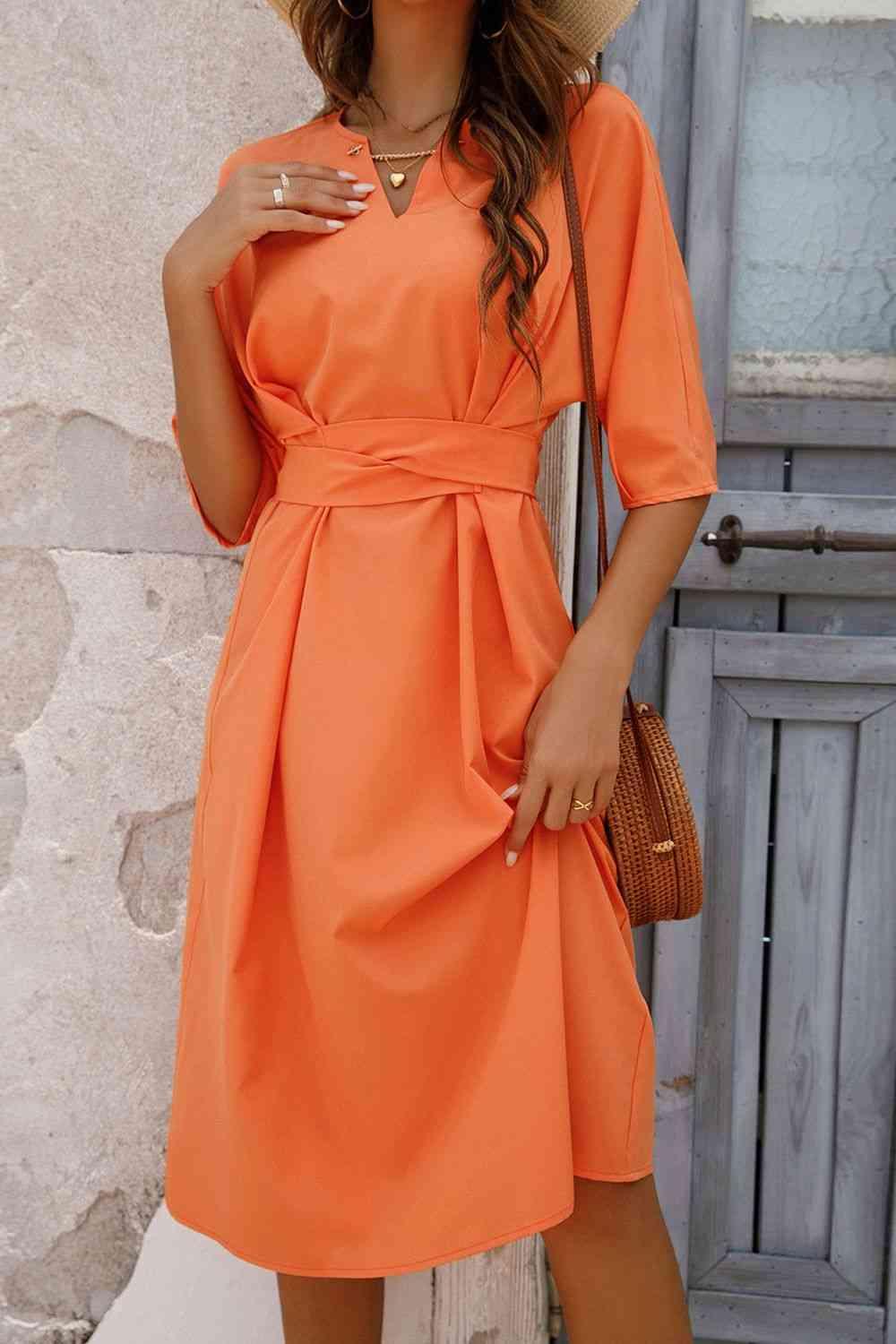 a woman wearing an orange dress and a straw hat