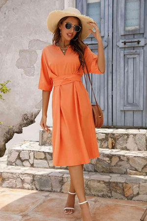 a woman wearing an orange dress and hat